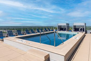 A large outdoor swimming pool with lounge chairs and a view of the horizon.